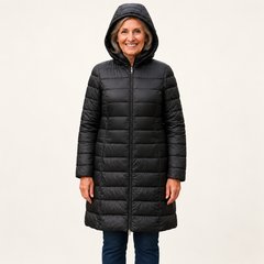 Mature British woman wearing the HELSA Black padded jacket on a clean warm off-white studio background
