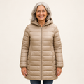 Mature British woman wearing the HELSA Champagne padded jacket on a clean warm off-white studio background