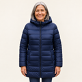 Mature British woman wearing the HELSA Navy Blue padded jacket on a clean warm off-white studio background